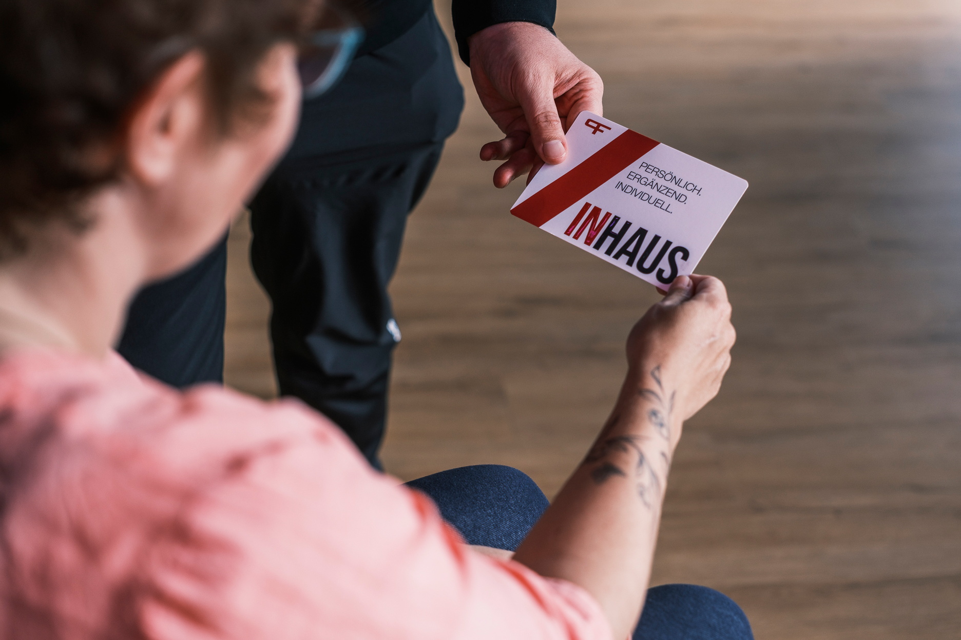 Ein Mann übrgibt einer Frau eine Karte, auf der INHAUS steht.