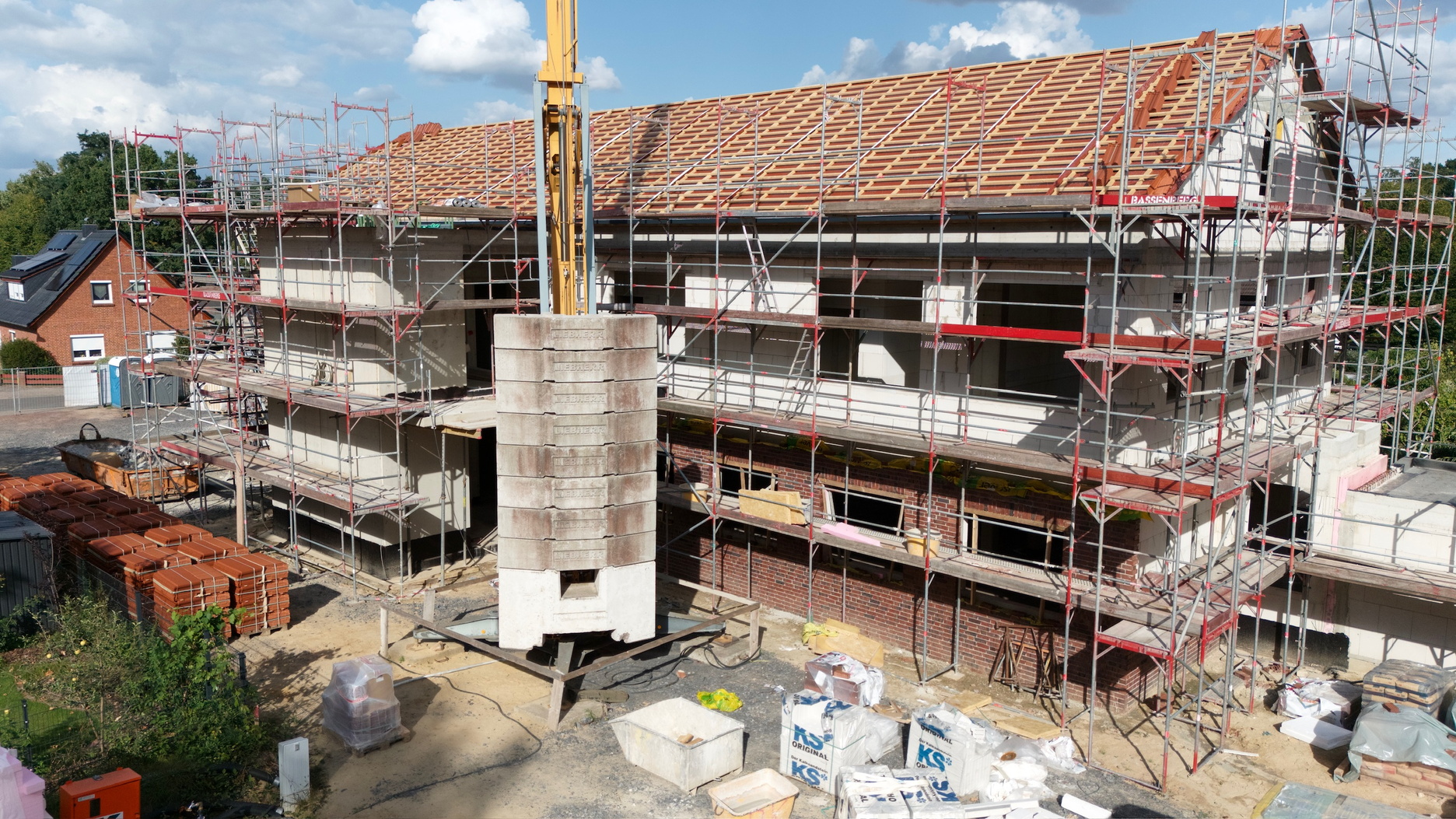 Baufortschritt eines Gebäudes im Rohbau, eingerüstet und bereit für den nächsten Schritt