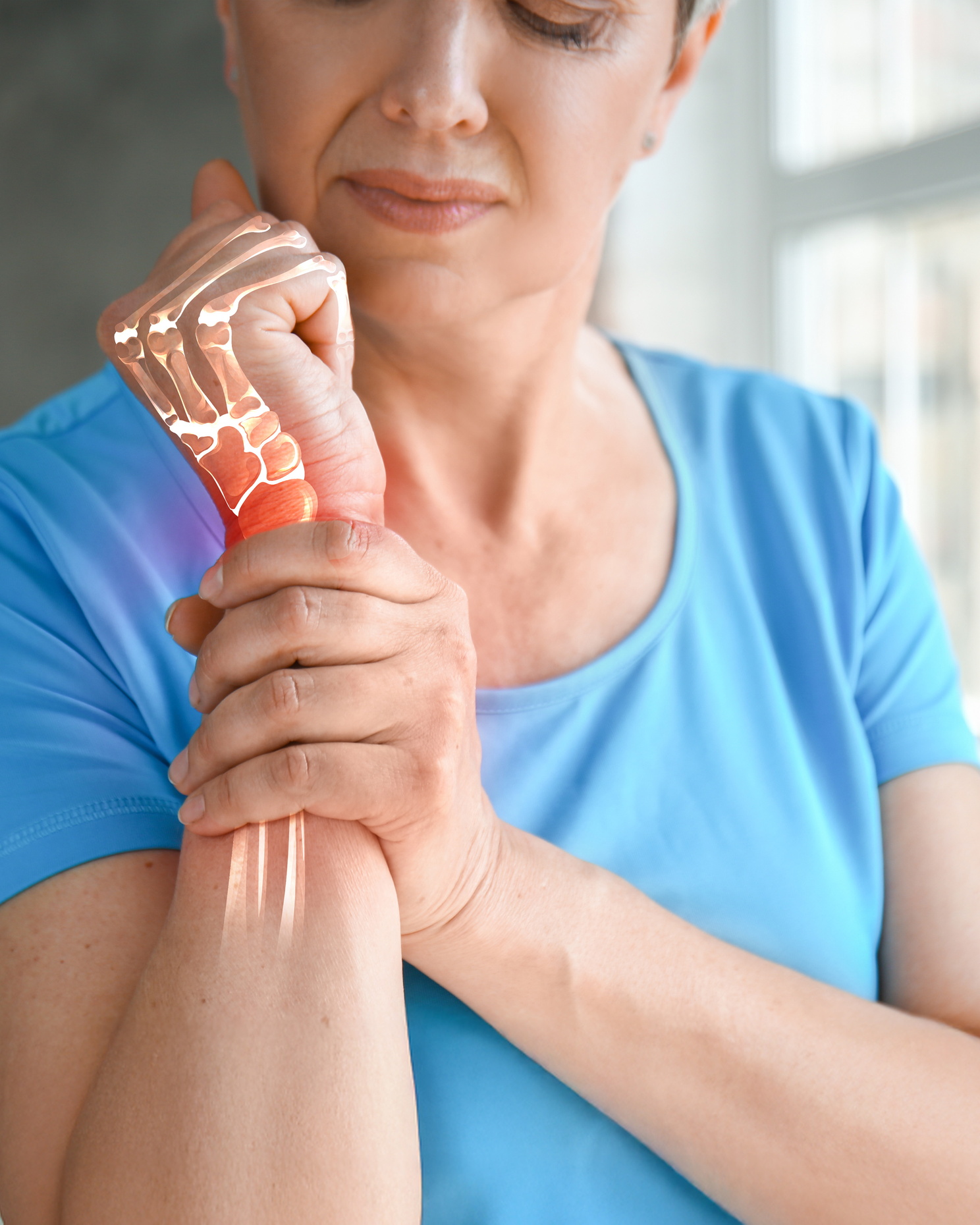 Eine Frau hält ihr schmerzendes Handgelenk mit hervorgehobener Knochenstruktur.
