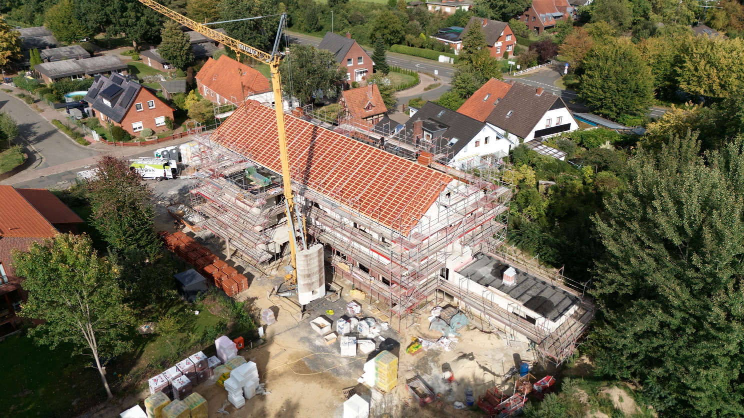 Ein im Bau befindliches Gebäude ist von einem Baugerüst umgeben, davor steht ein Bauzaun mit einem Banner zum entstehenden Therapiezentrum