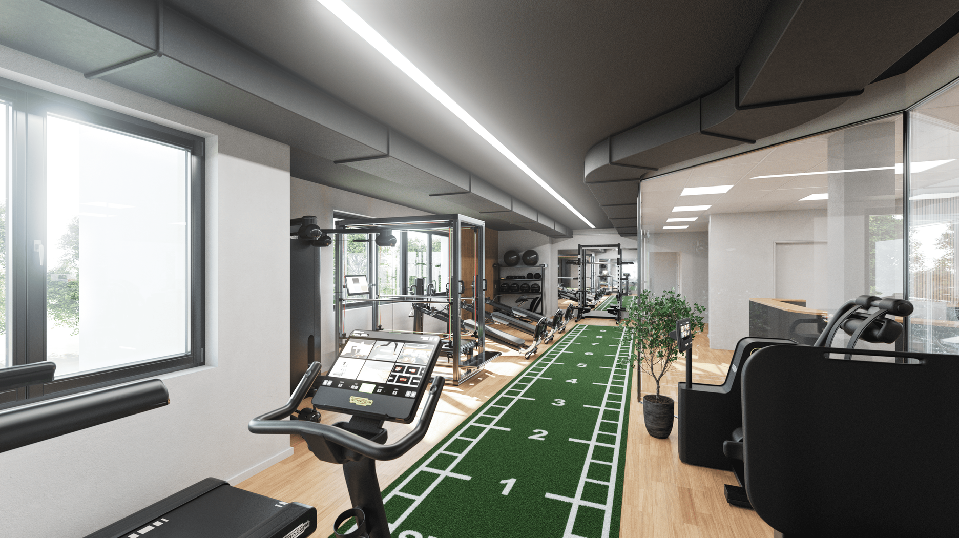 Heller Trainingsraum mit modernen Fitnessgeräten, Glasfront und grüner Sprintbahn in der Mitte