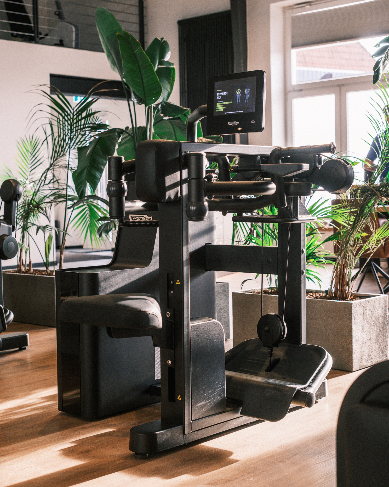 Ein Sportgerät der Marke Technogym mit Pflanzen im Hintergrund