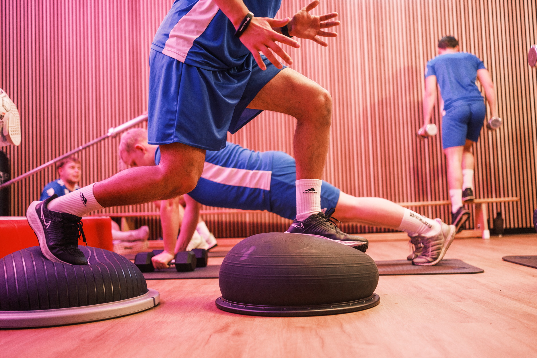 ChatGPT:  Mehrere Sportler trainieren in einem funktionellen Setting, während im Vordergrund eine Person ihre Balance und Kraft trainiert.