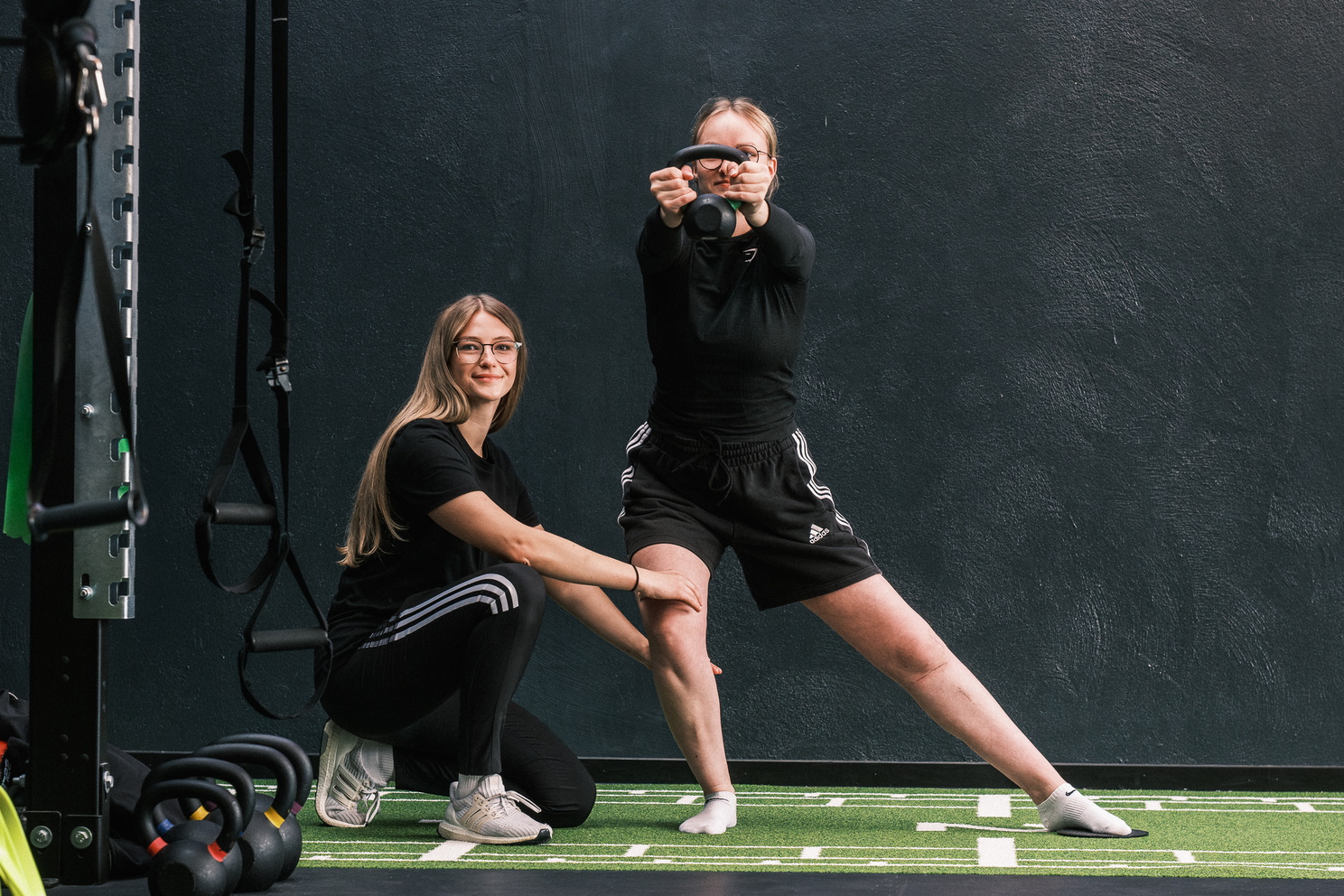 Eine Therapeutin unterstützt eine Patientin bei einer Übung mit einer Kettlebell