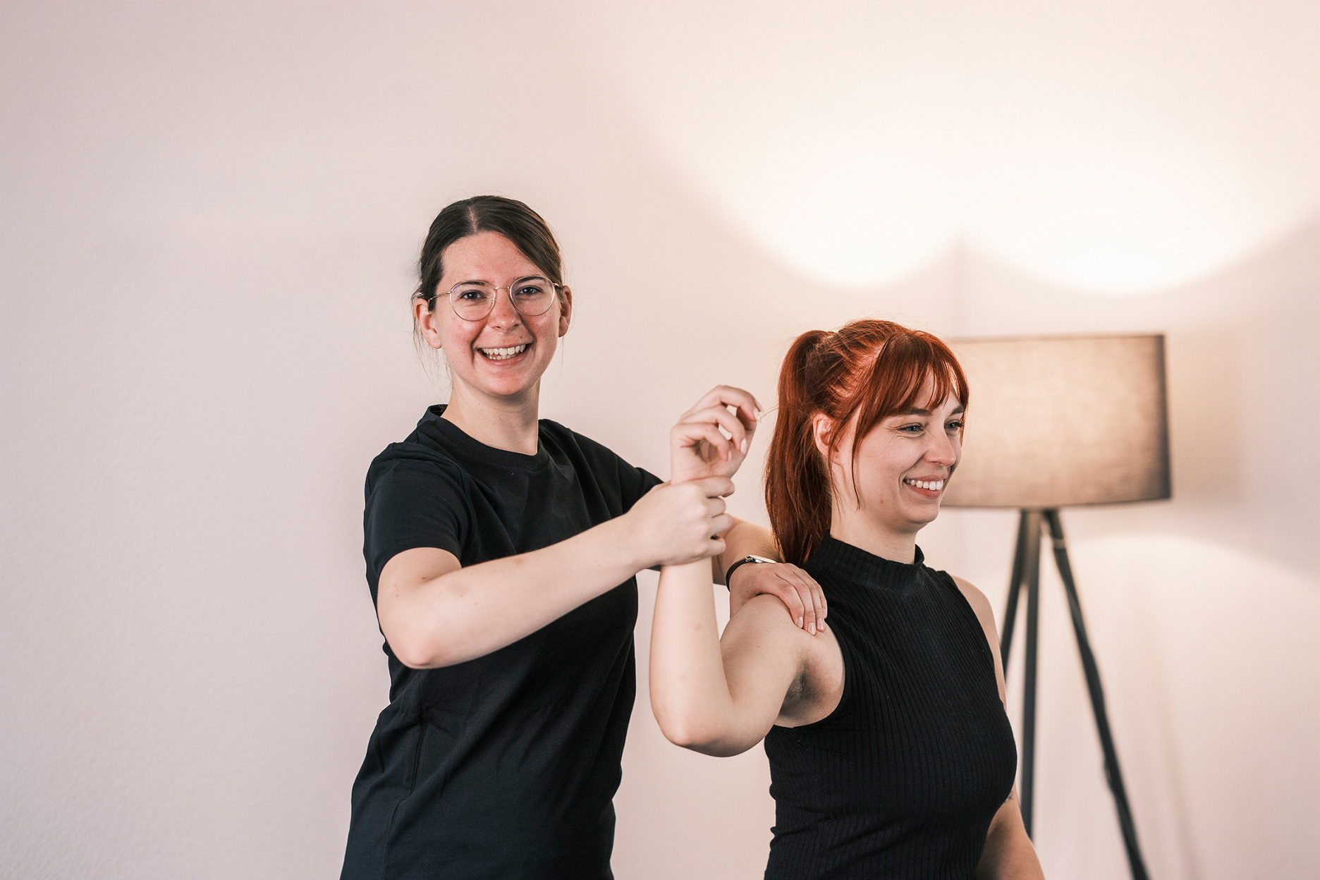 Eine Therapeutin unterstützt eine Person bei einer Mobilisationsübung für die Schulter.