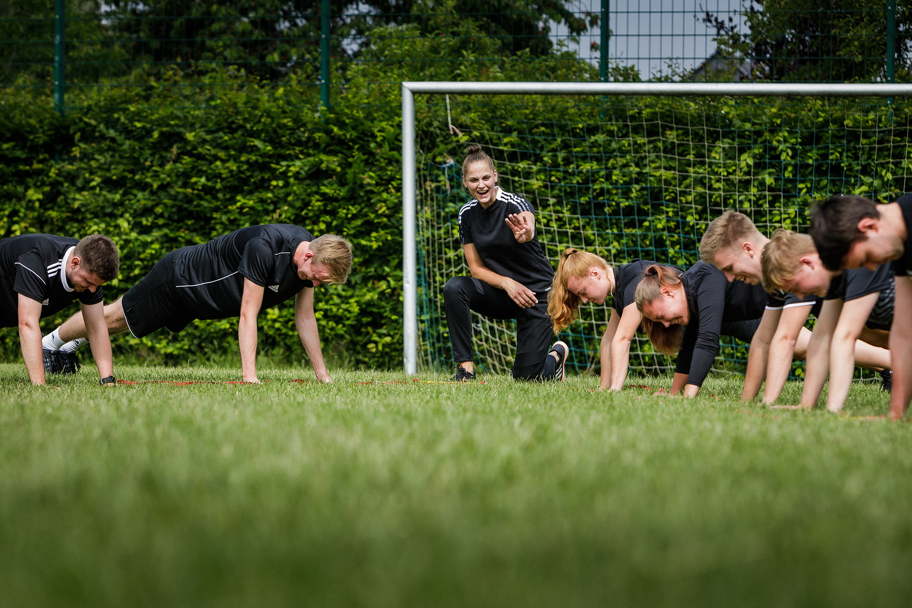 Eine Trainiern macht Übungen mit einer Sportmannschaft auf einem Fußballfeld