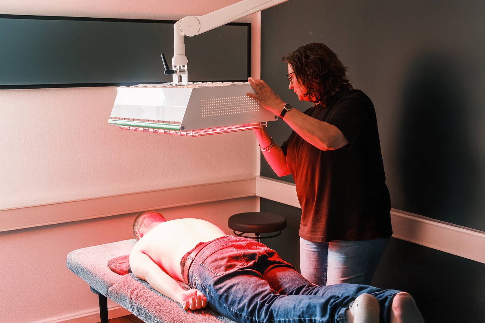 Eine Therapeutin behandelt den Kopf- und Kieferbereich einer liegenden Person.