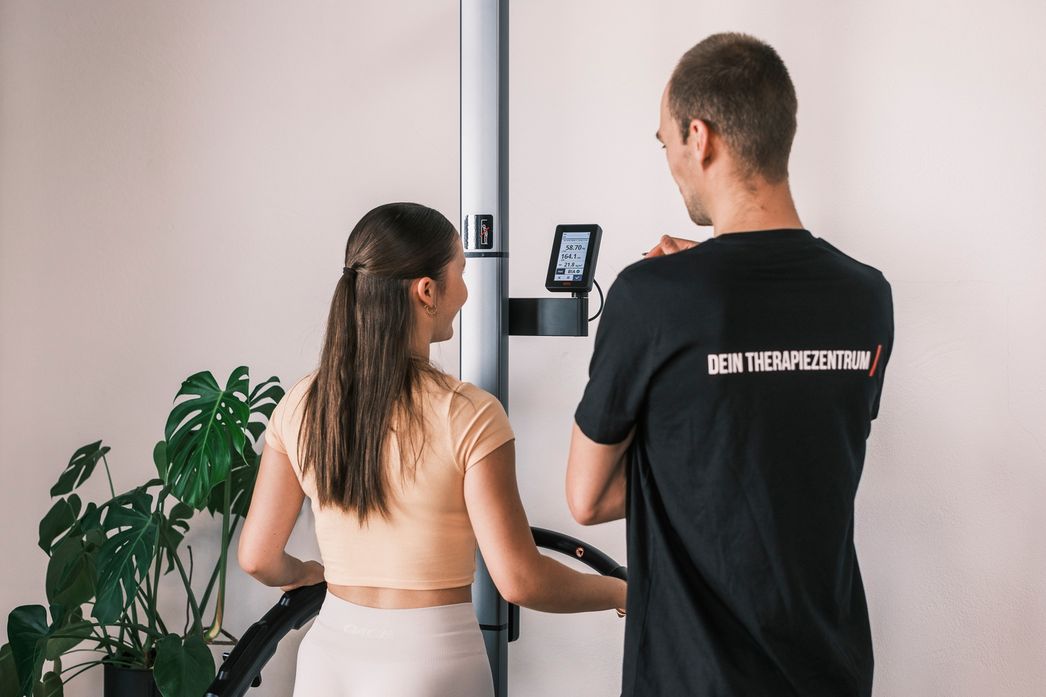 Eine Frau steht auf einer Körperanalysewaage, während ein Trainer die Anzeige erklärt