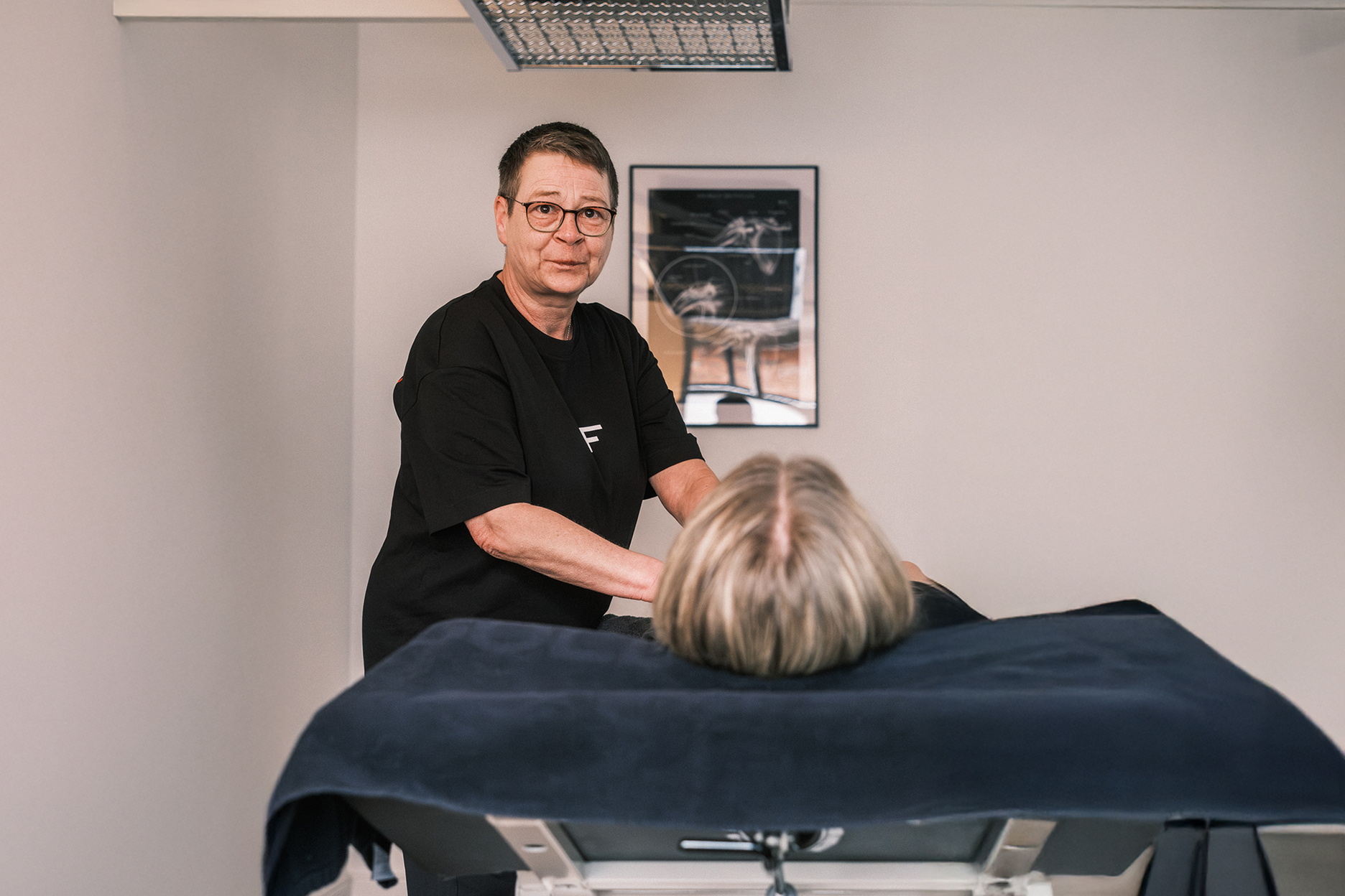 Eine Therapeutin führt bei einer liegenden Person eine Lymphdrainage durch.