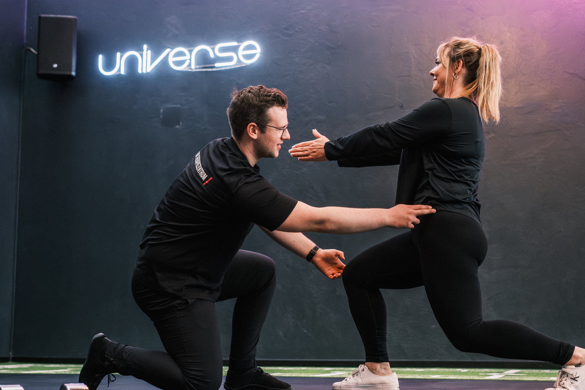 Ein Trainer leitet eine Trainierende bei einer Übung an.