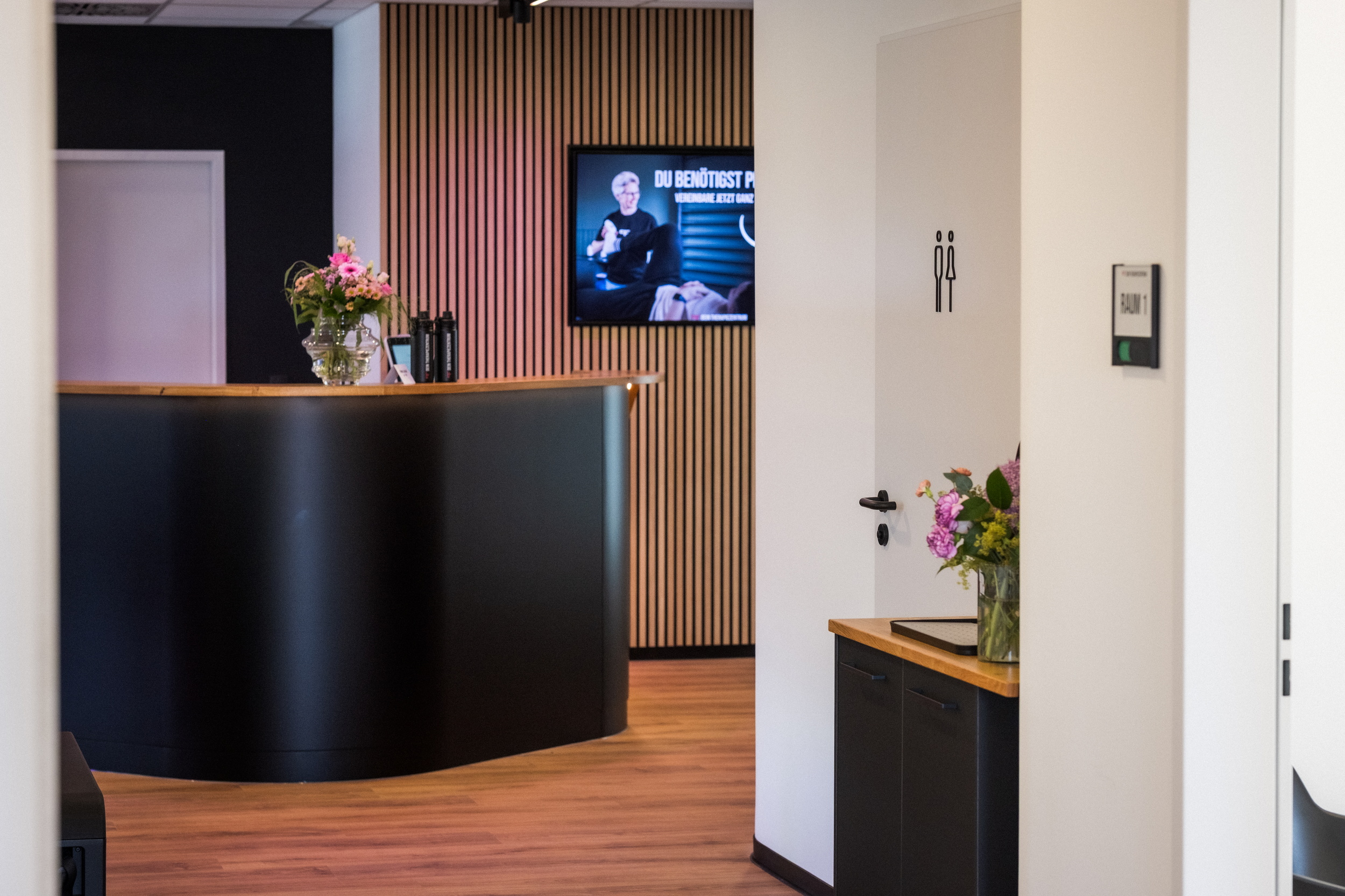 Moderner Empfangsbereich mit geschwungener Theke in Schwarz und Holz