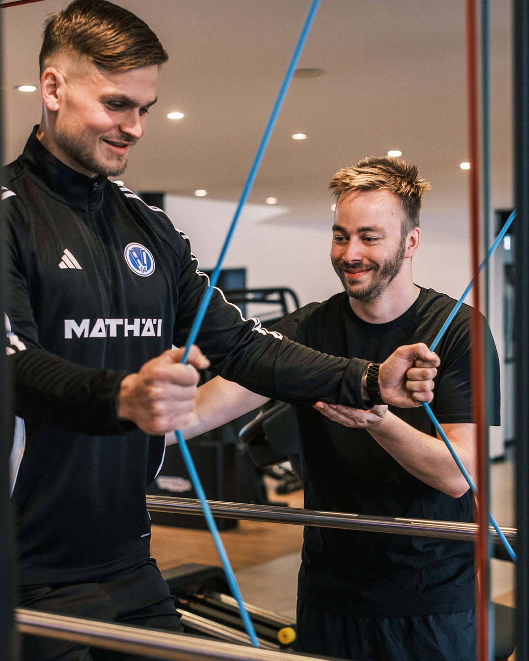 Ein Trainer unterstützt einen Sportler bei einer Übung mit Widerstandsbändern