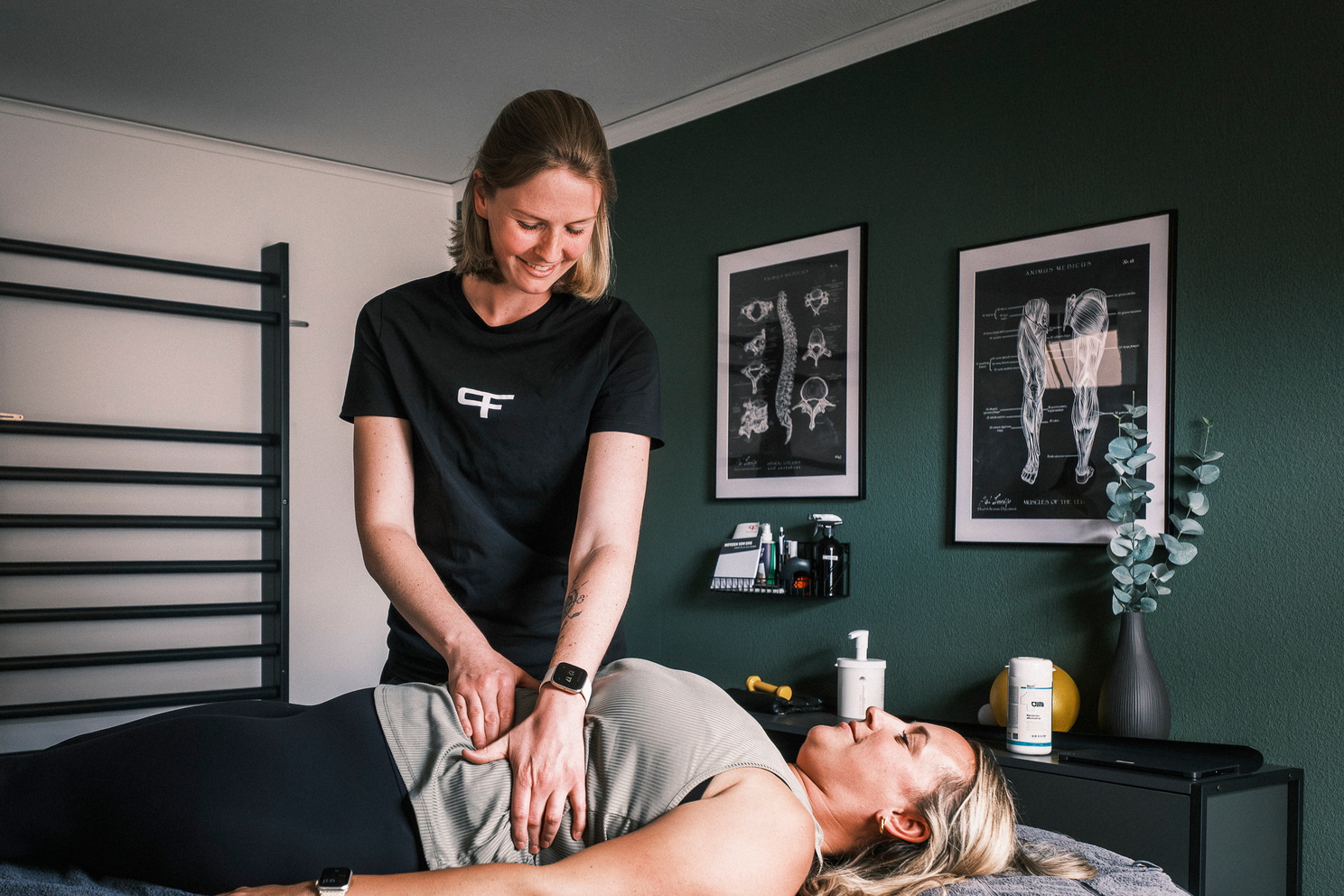 Eine Physiotherapeutin behandelt den Bauchbereich einer liegenden Patientin